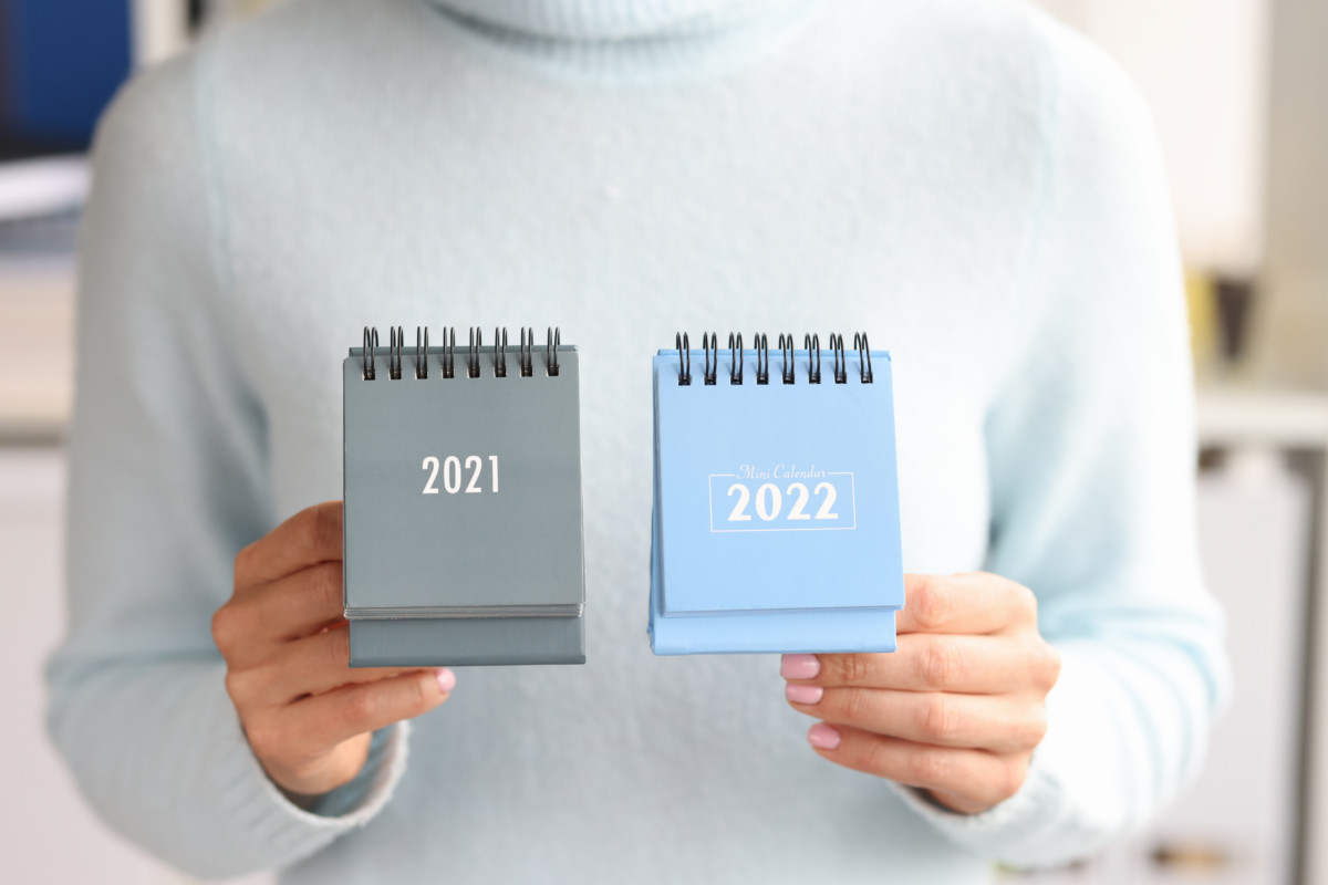 Woman holding calendar 2021 and 2022 closeup. Calendar year change